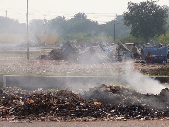 Piles of burning garbage in front of a shanty town outside the Agra Fort
