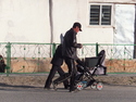 Guy pushing a tv in a baby stroller